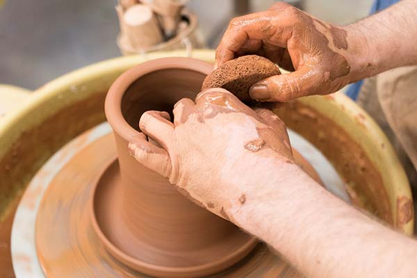 Person at pottery wheel with sponge